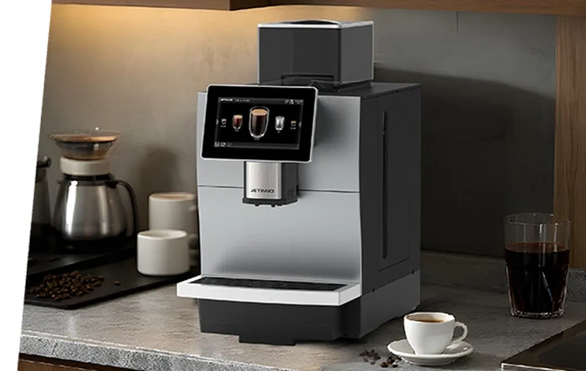 Cafetera superautomática instalada en la barra de una oficina, con taza servida